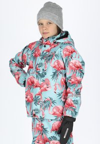 Blue waterproof jacket featuring a vibrant pink flamingo and palm leaf pattern, with elastic cuffs and a snap closure. Accessories include black gloves.
