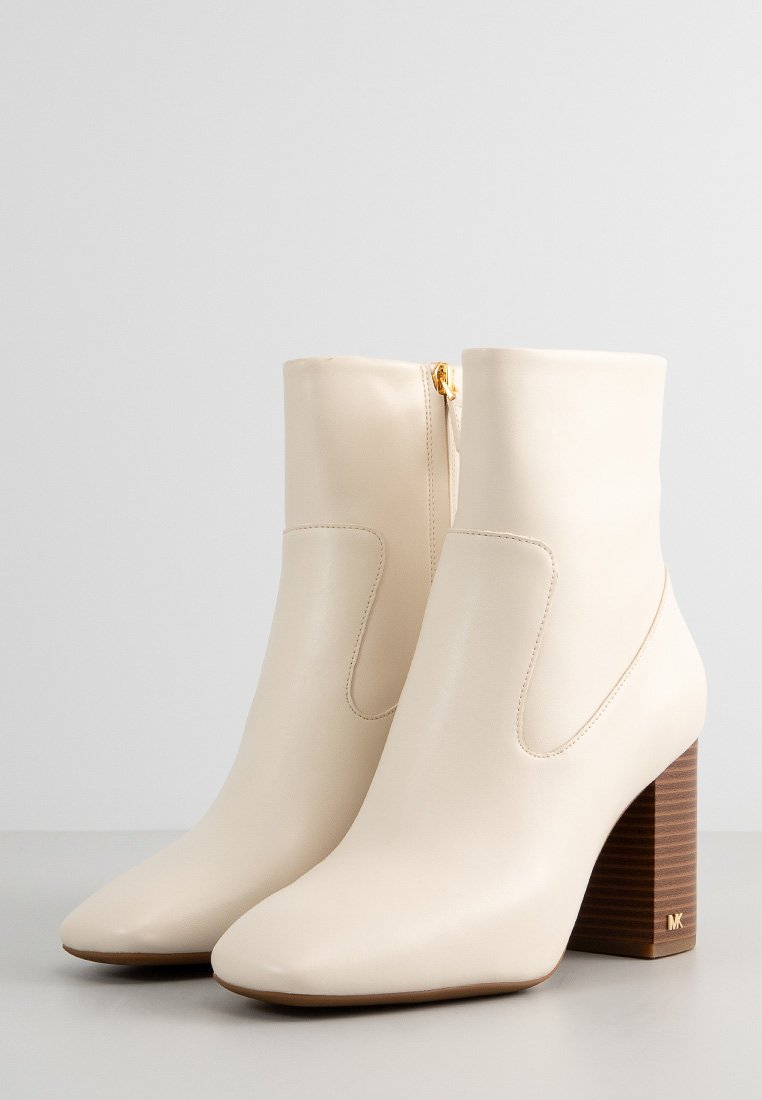 Stivaletti crema in pelle liscia, con punta a punta e tacco a blocco dal texture simile al legno. Dettaglio con chiusura a cerniera laterale.