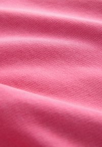 Tessuto rosa con una superficie texturizzata e piccoli motivi continui. Il materiale sembra morbido e flessibile, con pieghe sottili.
