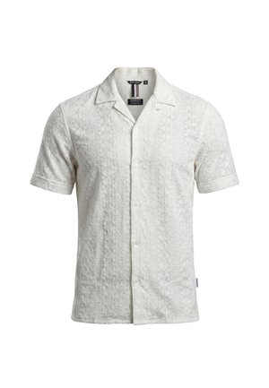 Chemise blanche à manches courtes avec motifs géométriques texturés, devant boutonné et col ouvert.