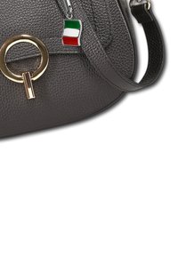 Sac en cuir texturé gris foncé avec un fermoir circulaire en or et un petit charme en forme de drapeau italien sur la sangle.