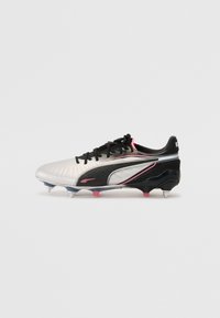 Black and white soccer cleat with a textured synthetic upper, pink accents, and conical studs on a solid black sole plate.