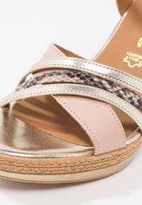 Sandale femme à bout ouvert avec brides métalliques dorées, beige et imprimé serpent sur une semelle plateforme texturée.