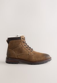 Bottes marron en cuir montantes avec doublure en fausse fourrure, bout arrondi et semelle en caoutchouc. Comporte des œillets métalliques et un détail de manchette à motif.
