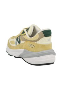 Zapatillas New Balance 990 en amarillo, beige y verde. Materiales de ante y malla, cuello acolchado y suela blanca con acentos grises.