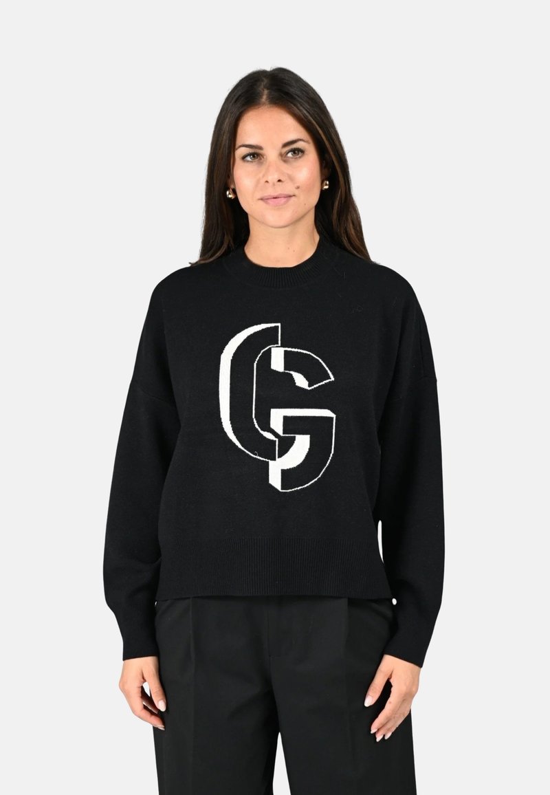 Pull noir avec un grand logo graphique blanc au centre. Le design possède un col et des poignets côtelés, avec une coupe décontractée.