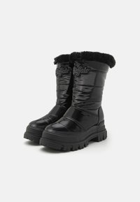Botas negras, brillantes y impermeables con parte superior acolchada, ribete de piel sintética y suela resistente. Presenta una marca en el lateral.