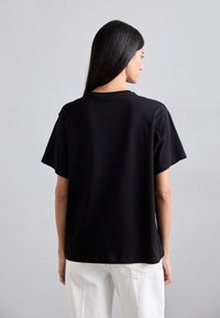 Black cotton T-shirt with short sleeves, relaxed fit, and a crew neck. Smooth texture, minimal design, and no visible patterns or accents.