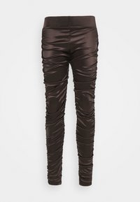 Leggings en satin marron avec une coupe ajustée, dotés d'une texture froncée et d'un design élégant. Ceinture élastique pour plus de confort, sans matériel visible.
