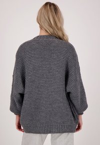 Overmaat grijze gebreide trui met een textuurfinish, wijde mouwen en een geribbelde zoom. Heeft een ronde halslijn en een ontspannen silhouet.