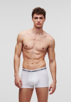 Witte boxershort met een zwarte stoffen tailleband met de tekst "KARL LAGERFELD". Gladde textuur, getailleerd ontwerp en een klassieke korte stijl.