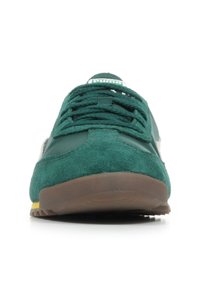 Scarpa sportiva verde in materiali scamosciati e sintetici, con punta rotonda, design con lacci e suola in gomma marrone con accenti gialli.