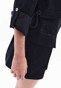 Marinblå cargo shorts med en avslappnad passform, med flera fickor, uppvikta ärmar och en justerbar dragsko-detalj.