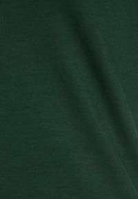Primer plano de una tela acanalada de color verde oscuro, que muestra una textura suave y un patrón consistente, adecuada para diversas aplicaciones textiles.