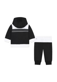Ensemble de survêtement bicolore noir et blanc comprenant un sweatshirt à capuche avec une rayure blanche sur le col et un pantalon assorti avec un design à poignet ajusté.