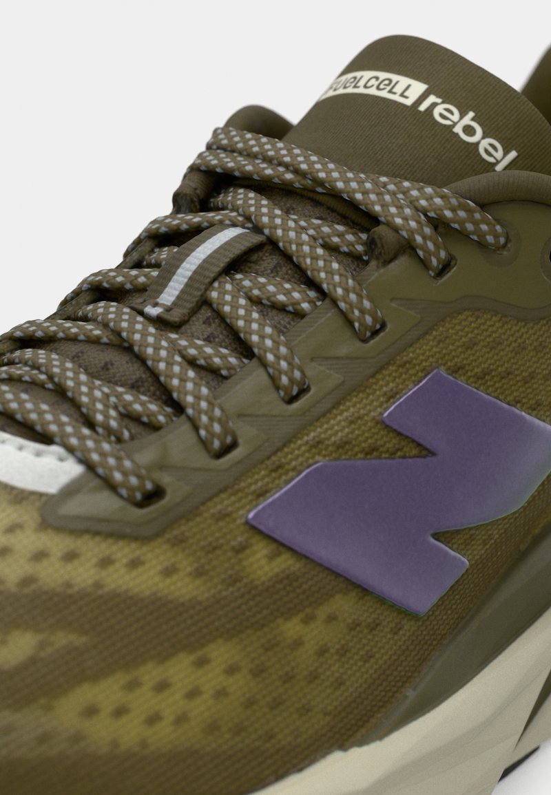 Scarpa sportiva verde e marrone con superiore in rete, suola spessa, logo viola, lacci testurizzati e colletto per caviglia imbottito.