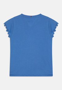 T-shirt blu a maniche corte con maniche a volant, scollatura rotonda e superficie liscia. Presenta una striscia verticale a contrasto sul retro.