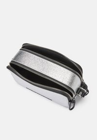 Sølv metallisk rektangulær veske med to glidelåsrom, svart interiør og sølvfargede detaljer. Glatt tekstur, kompakt design.