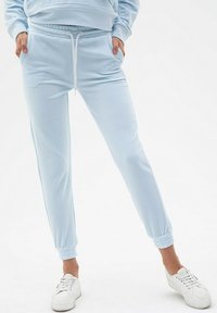 Jasnoniebieskie dresy wykonane z miękkiego materiału, z elastycznym paskiem w talii, sznurkiem, bocznymi kieszeniami i ściągaczami przy kostkach.