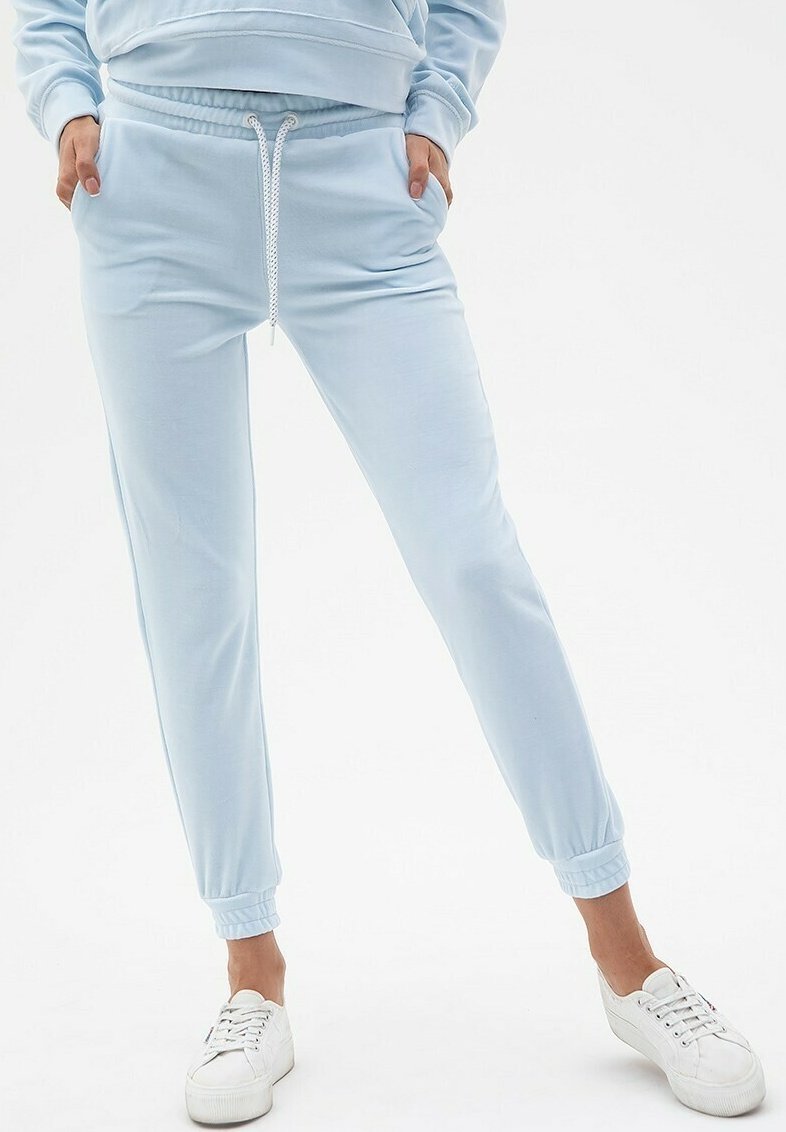 Jasnoniebieskie dresy wykonane z miękkiego materiału, z elastycznym paskiem w talii, sznurkiem, bocznymi kieszeniami i ściągaczami przy kostkach.