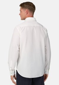 Witte lange mouwen shirt met kraag, knoopmanchetten en een gebogen zoom. Gemaakt van een gladde, lichte stof.