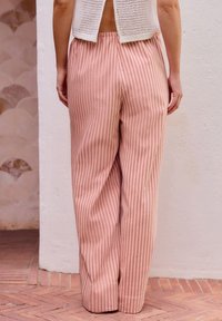 Pantaloni larghi a righe rosa realizzati in tessuto morbido, caratterizzati da righe bianche verticali e una vita elasticizzata per il massimo comfort.