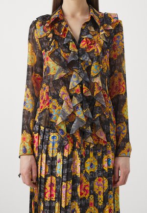 Conjunto de blusa negra transparente y falda plisada con patrones barrocos ornamentados coloridos y volantes delanteros en capas.