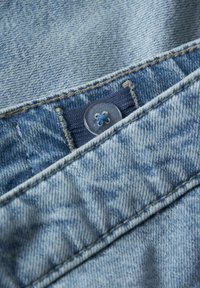 Svijetloplava jeans tkanina s vidljivim kopčanjem na dugme. Ima teksturiranu površinu s blagim izblijeđenjem i kontrastnim detaljima šivanja.