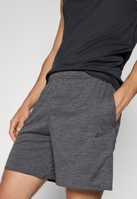 Calções atléticos cinzentos feitos de um material leve e texturizado, com bolsos laterais e uma cintura elástica para maior conforto.