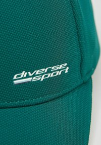 Zielona czapka sportowa z teksturowanej tkaniny, z białym logo "diverse sport" z przodu i usztywnionym daszkiem.