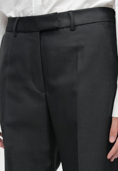 Μαύρο παντελόνι από λεία ύλη, με επίπεδο μπροστινό μέρος, πλαϊνές τσέπες και κομψή ζώνη με διακριτική γυαλάδα.