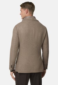 Blazer in misto lana marrone con rever a punta, texture liscia, spacchetto posteriore singolo e bottoni neri sulle maniche.