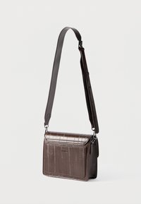 Geantă de umăr maro din piele ecologică cu textură de crocodil, prevăzută cu o curea ajustabilă și o clapă cu închidere magnetică. Design compact.