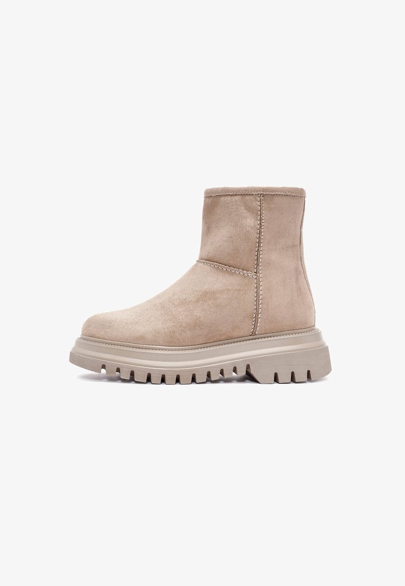 Tan suède enkellaars met een chunky beige zool, met contrasterende stiksels en een ronde teen, ontworpen voor comfort en duurzaamheid.