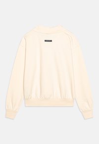 Sudadera color crema con cuello alto, puños acanalados y cintura acanalada. Presenta un pequeño logotipo negro en la parte superior de la espalda. Textura suave.