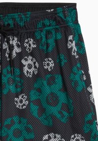 Pantalones cortos de malla negra con un patrón floral en verde azulado y blanco, con una cintura elástica y detalle de cordón.