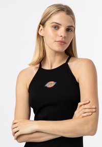 Čierny top na ramienka s tenkými popruhmi, s viacerými farebnými kruhovými logami a textom "Dickies" na prednej strane. Hladká tkanina.