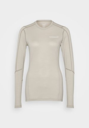 Világos bézs színű, hosszú ujjú ing, sima anyagból készült, kerek nyakkivágással és apró varrási díszítésekkel, a mellkason logóval ellátva.