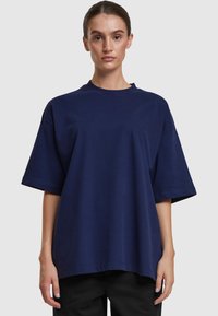 Camiseta de gran tamaño de color azul marino, confeccionada en algodón, con cuello redondo, mangas cortas y un corte relajado con un dobladillo recto.