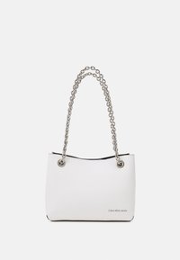 Bílá taška přes rameno z umělé kůže se stříbrným řetízkovým popruhem, s kovovými průchodkami a černým vnitřkem. Na přední straně je zobrazeno logo.