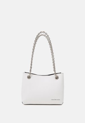 Borsa a mano in ecopelle bianca con tracolla a catena argentata, caratterizzata da occhielli in metallo e interno nero. Logo visibile sul davanti.