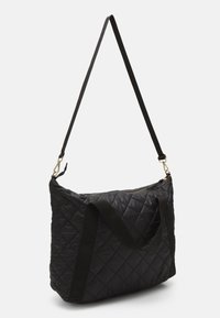 Sac noir matelassé à texture douce, doté d'une fermeture éclair, de deux poignées et d'une bandoulière ajustable avec des accents en métal doré.