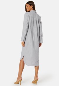 Abito camicia grigio a righe con colletto, maniche lunghe, polsini abbottonati e spacchi laterali. Realizzato in tessuto leggero per il massimo comfort.