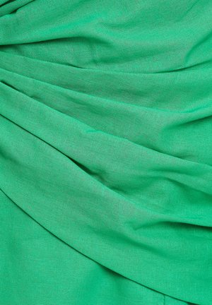 Tela verde con una apariencia texturizada y tejida, con pliegues y arrugas drapeadas, que muestran profundidad y movimiento.