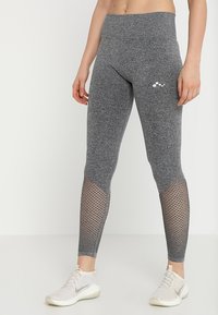 Szare legginsy wykonane z elastycznego materiału, z siateczkowymi panelami na dolnych partiach nóg oraz gładką talią. Zawierają małe logo na biodrze.