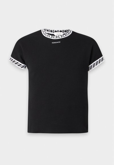 Μαύρο κοντομάνικο πουκάμισο με λευκή διακοσμητική λεπτομέρεια στο γιακά και τα μανίκια, με το λογότυπο της Versace κεντραρισμένο κάτω από το λαιμόκοψη.