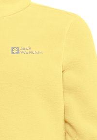 Geel fleece jack met een kwart-rits hals, zachte textuur en een blauw geborduurd logo op de linkerkant van de borst.