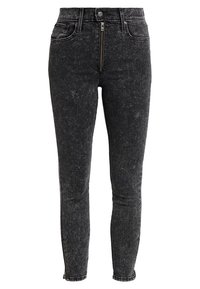 Vaqueros pitillo de mezclilla negra con una textura ligeramente descolorida, con cierre frontal de cremallera y cremalleras laterales en el dobladillo para un ajuste ajustable.