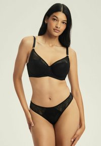 Czarny koronkowy stanik i dopasowany stringi z misternymi wzorami, wsparciem w postaci fiszbin, regulowanymi ramiączkami i bezszwowym designem.