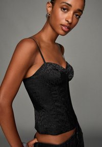 Schwarzes Satin-Corsage-Oberteil mit einem Leopardenmuster, das schlanke Träger und ein tailliertes Design aufweist, das die Taille betont.